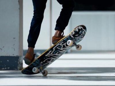 A skateboarder performing a trick indoors with stylish footwear and graffiti skateboard design.