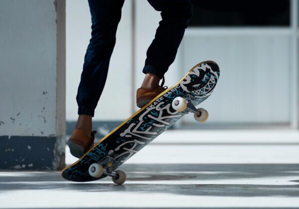A skateboarder performing a trick indoors with stylish footwear and graffiti skateboard design.