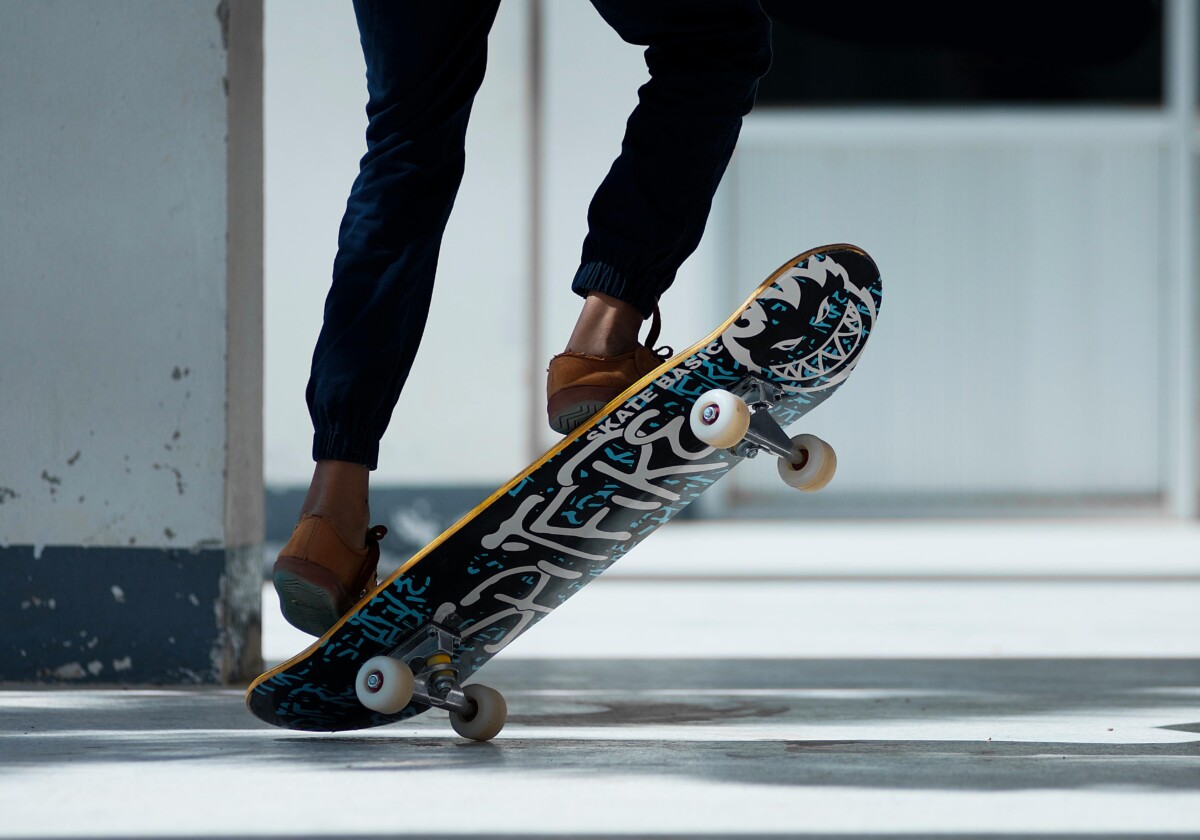 A skateboarder performing a trick indoors with stylish footwear and graffiti skateboard design.