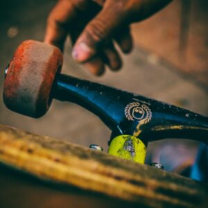Detail shot of skateboard trucks and wheels with a hand, showcasing urban skate culture.