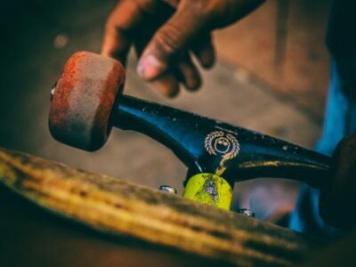 Detail shot of skateboard trucks and wheels with a hand, showcasing urban skate culture.